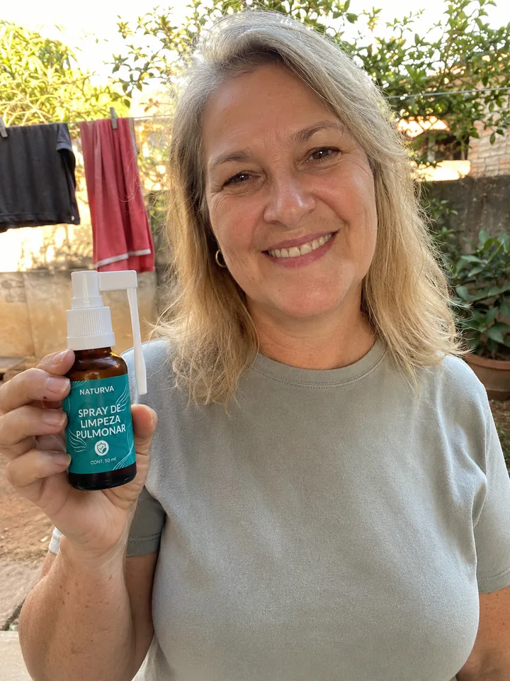 Cliente no quintal de casa segurando o frasco do Naturva™ Spray de Limpeza Pulmonar